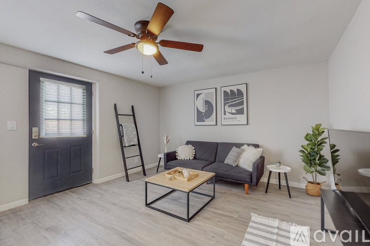 A living room with a grey couch, a coffee table, and a ceiling fan.