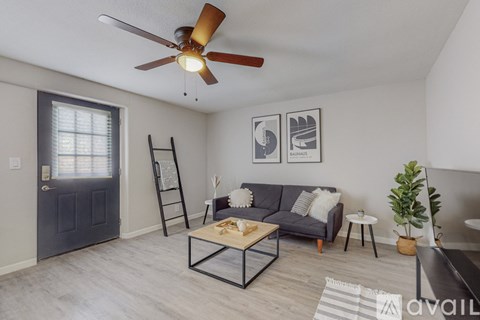 A living room with a grey couch, a coffee table, and a ceiling fan.