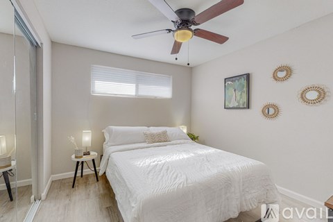 A bedroom with a white bed and a ceiling fan.