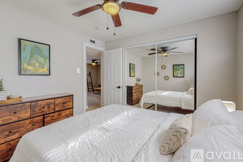 A bedroom with a large bed and a ceiling fan.