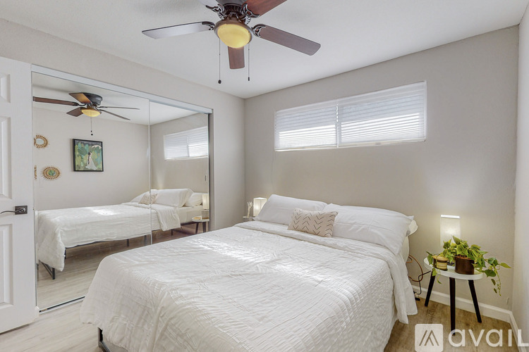 A bedroom with two beds, a ceiling fan, and a small table with a plant on it.
