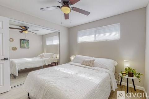 A bedroom with two beds, a ceiling fan, and a small table with a plant on it.