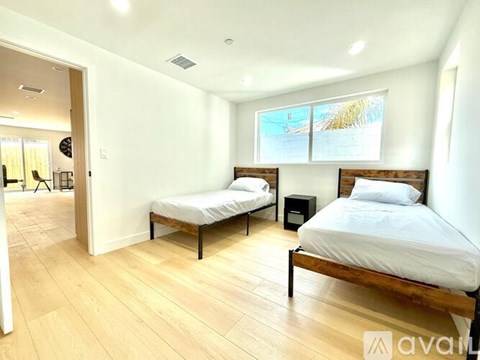 A bedroom with two beds and a wooden floor.