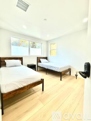 A bedroom with two beds and a chair.