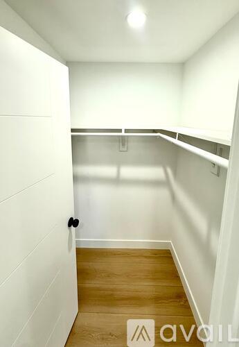 A white hallway with a black door and wooden floor.