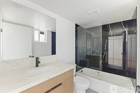 A modern bathroom with a white sink and a large mirror.