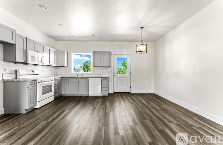 A spacious kitchen with wooden floors and white appliances.