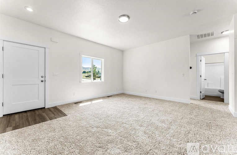 A white room with a carpeted floor and a window.