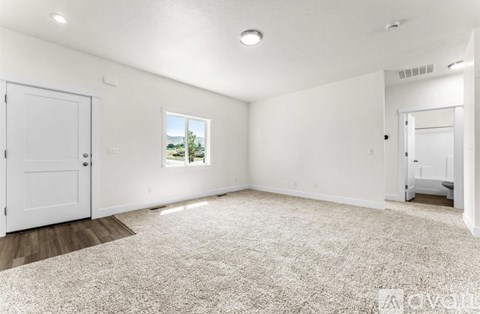 A white room with a carpeted floor and a window.