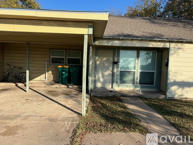 A house with a tan siding and a green trash can.