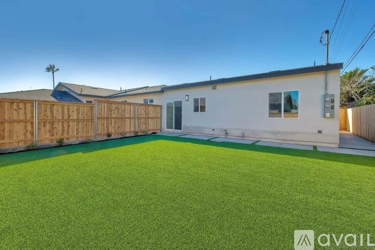 A backyard with a wooden fence and a green lawn.