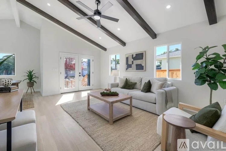 A living room with a white couch, a wooden coffee table, and a ceiling fan.