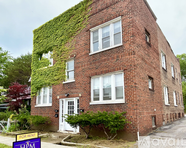 A red brick building with a sign that says For Rent.