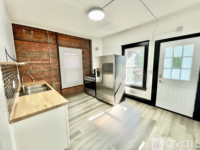A kitchen with a brick wall and wooden floors.