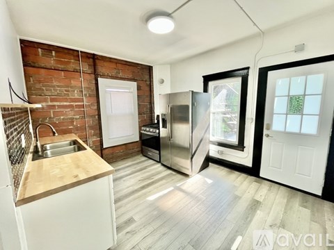 A kitchen with a brick wall and wooden floors.