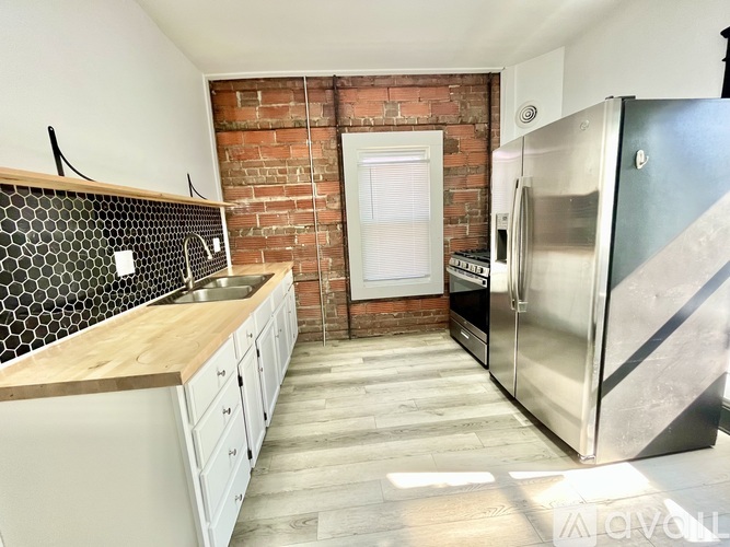 A kitchen with a brick wall and a refrigerator.