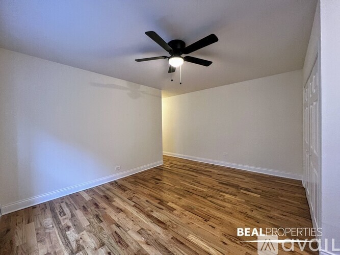 A room with a ceiling fan and wooden flooring.