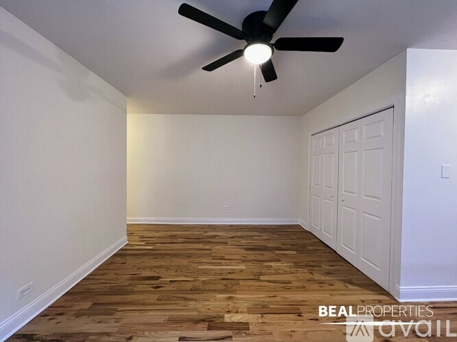 A room with a ceiling fan and wooden flooring.