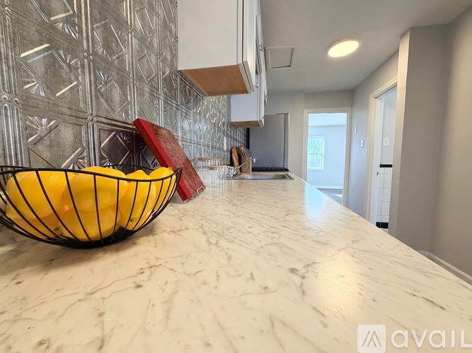 A bowl of lemons sits on a marble countertop in a kitchen.