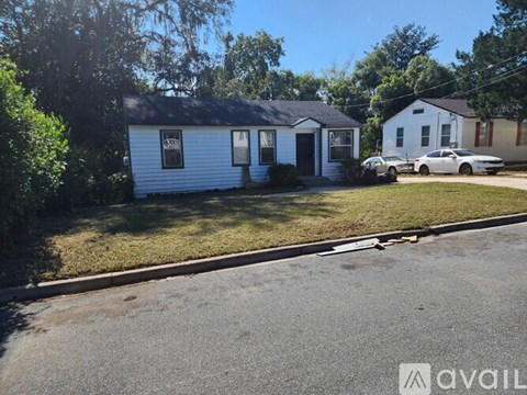 A small white house with a car parked in front of it.