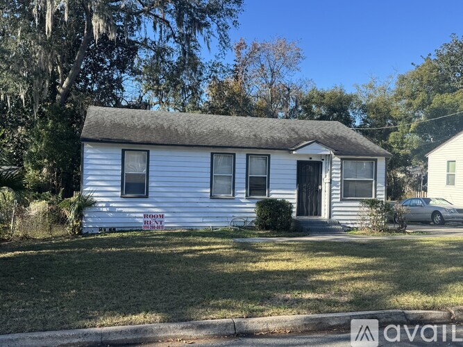 A small white house with a grey roof and a sign that says "ROOM RENT".