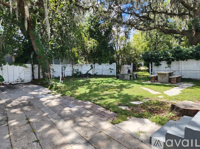 A backyard with a white fence and a tree.