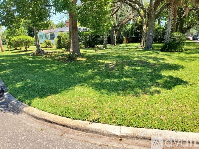A green lawn with trees and a house in the background.