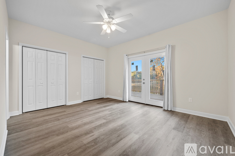 A spacious room with a ceiling fan and a view of a cityscape through a glass door.