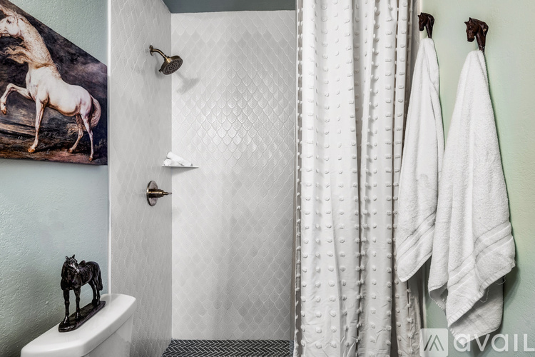 A bathroom with a toilet, a shower curtain, a towel and a painting of a giraffe.