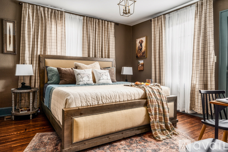 A bedroom with a large bed and a window with curtains.