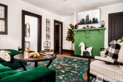 A living room with a green couch, a green fireplace, and a painting of a city skyline on the wall.