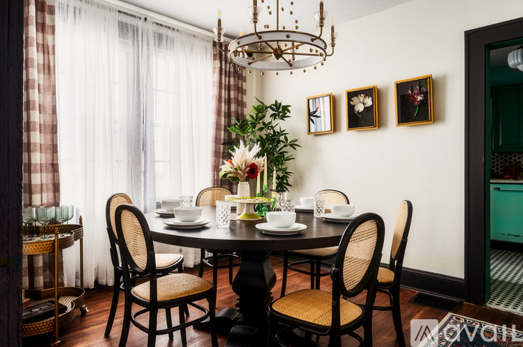 A dining room with a table set for four and a chandelier hanging from the ceiling.
