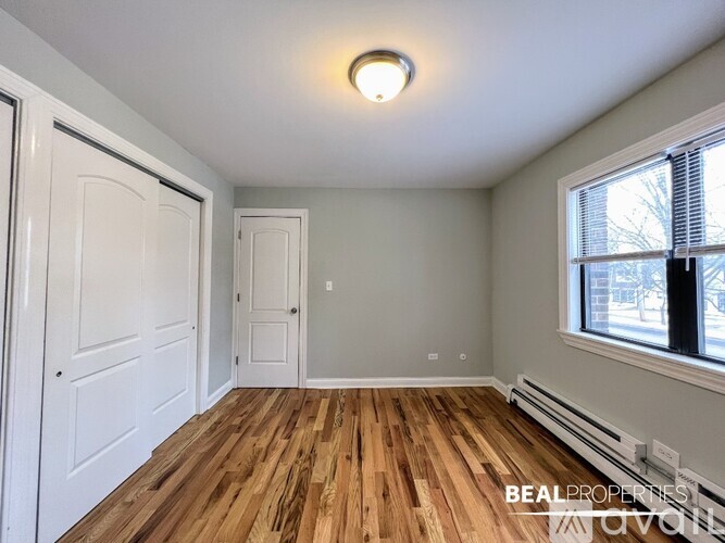 A room with wooden floors and white walls, with a window on the right side.