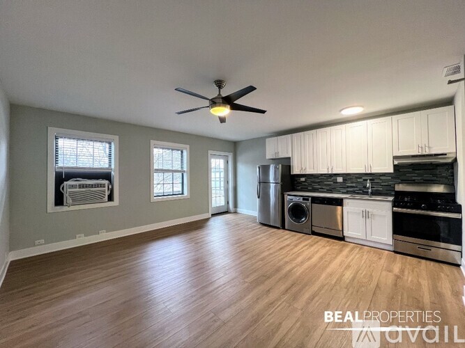 A spacious kitchen with white cabinets and a wood floor.