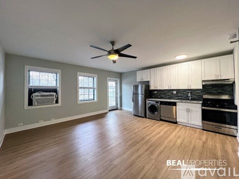 A spacious kitchen with white cabinets and a wood floor.