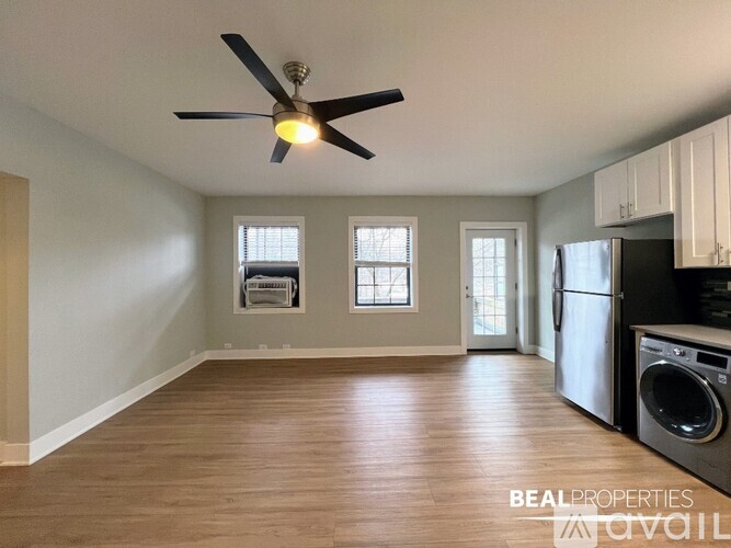 A BEAL PROPERTIES image of a kitchen with a fan, washing machine, and wooden floors.