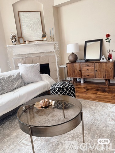A living room with a white couch, a glass coffee table, and a wooden cabinet.