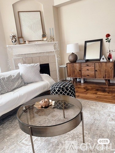A living room with a white couch, a glass coffee table, and a wooden cabinet.