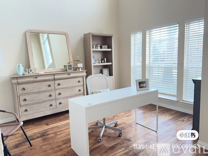 A white desk with a mirror and a chair in a room with wooden floors.