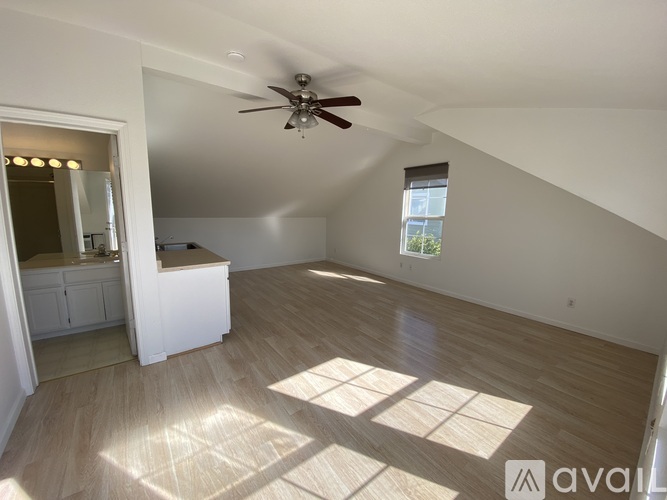 A spacious room with a ceiling fan and a window letting in natural light.