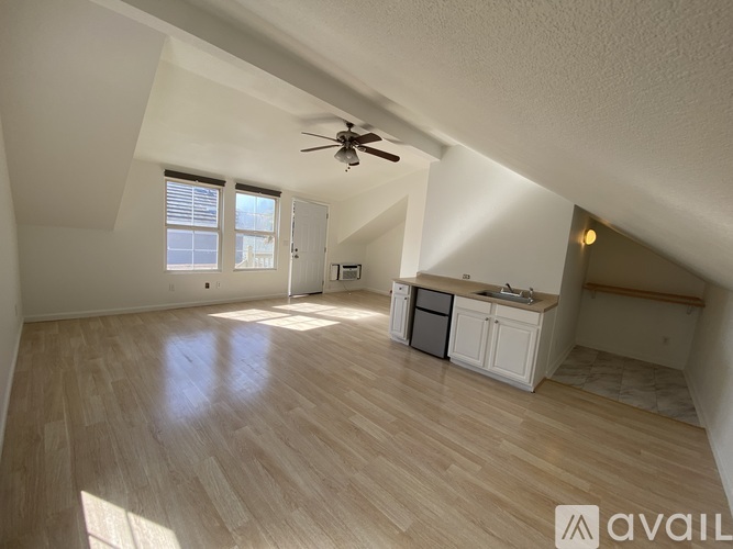 A spacious room with wooden flooring and a ceiling fan.