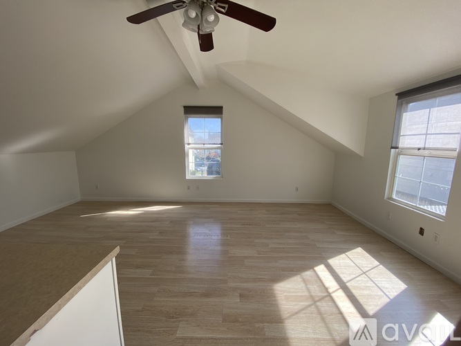 A room with a ceiling fan and wooden flooring.