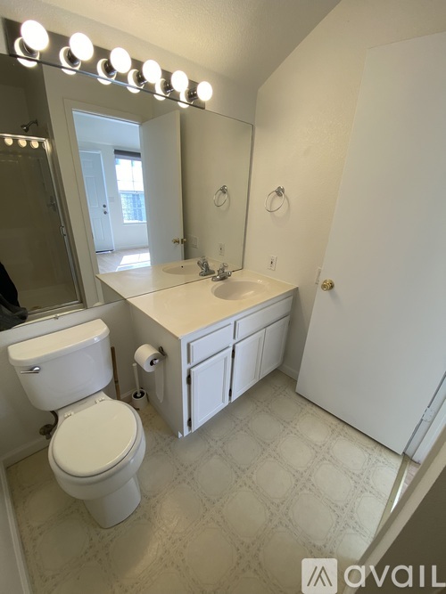 A bathroom with a toilet, sink, and mirror.