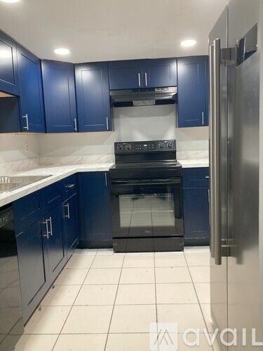 A kitchen with blue cabinets and a stainless steel refrigerator.