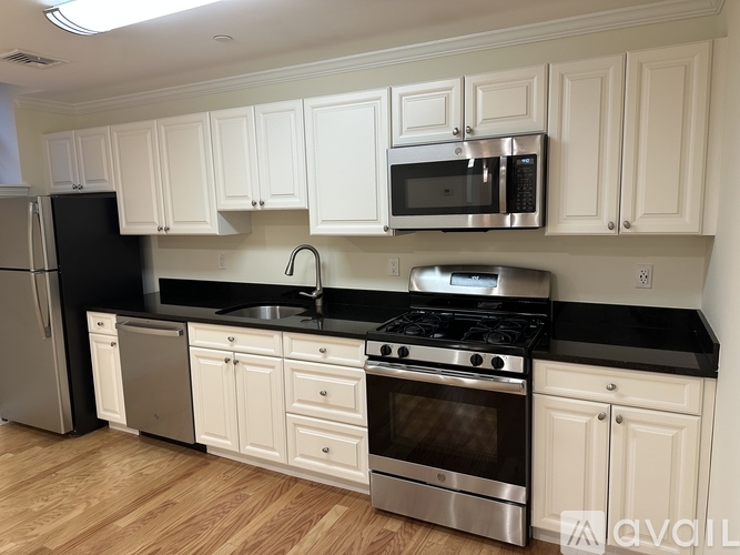 A kitchen with white cabinets and black countertops.