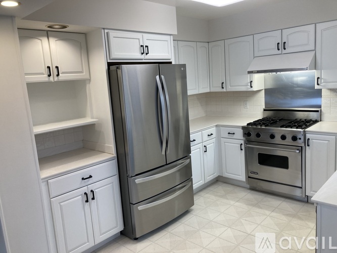 A modern kitchen with white cabinets and stainless steel appliances.