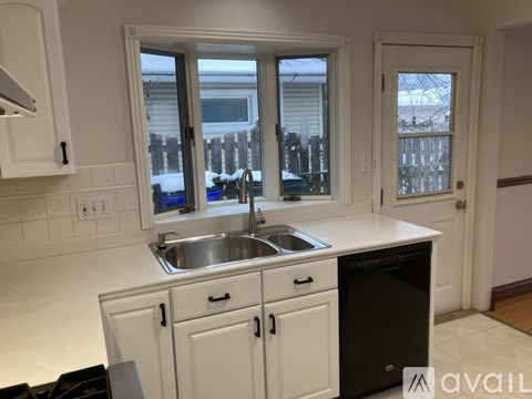 A kitchen with white cabinets and a black dishwasher.