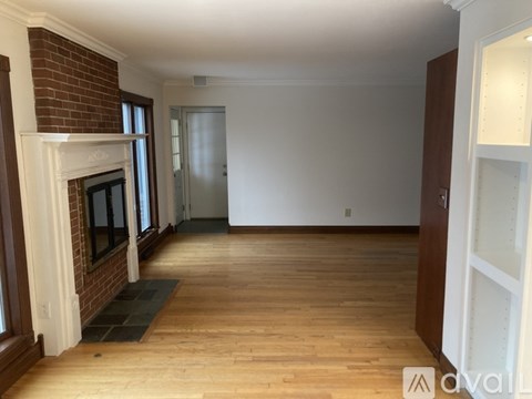 A room with a brick fireplace and wooden floors.
