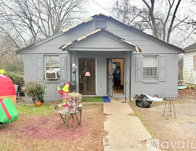 A small house with a grey exterior and a red and green inflatable object in the front yard.