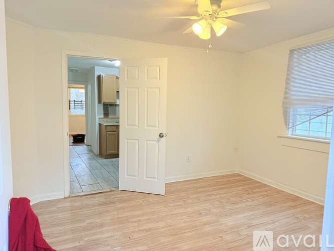 A room with a ceiling fan and a door leading to another room.